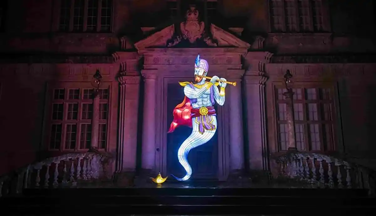 Illuminated genie lantern figure rising from a golden lamp with a flute, for Arabian Nights themed events