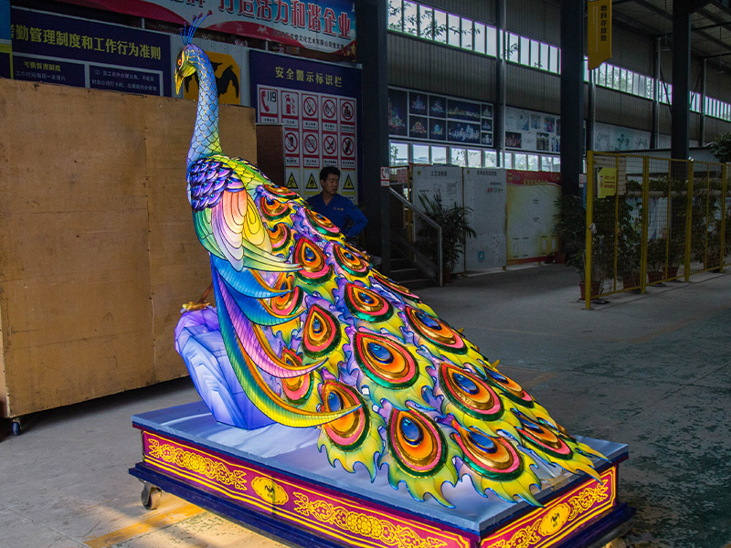 Side view of peacock lantern sculpture showing detailed feather layering on decorative base