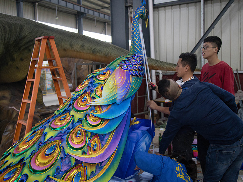 Artisans assembling a large peacock lantern in the workshop with steel frame visible