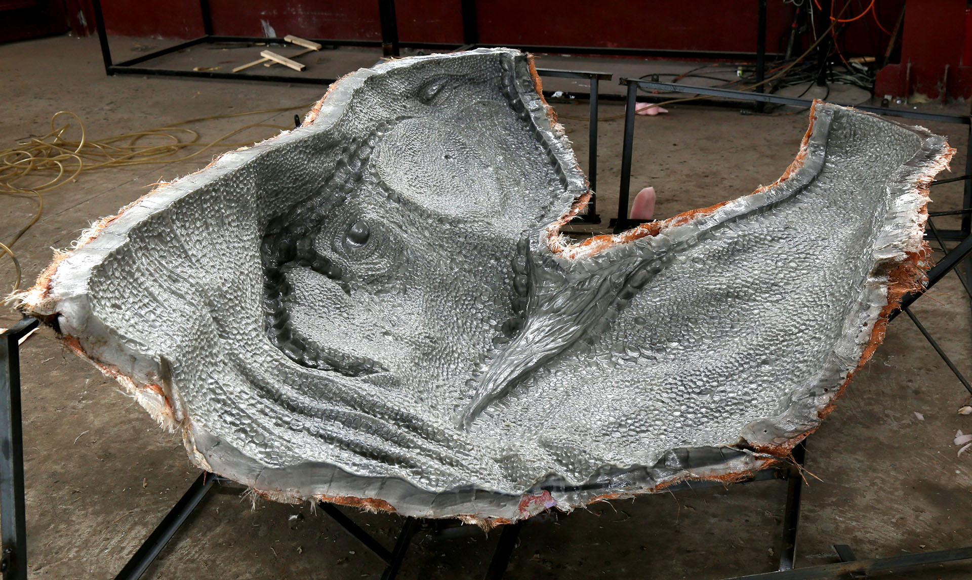 Molded silicone skin casting process showing detailed dinosaur skin texture inside fiberglass mold