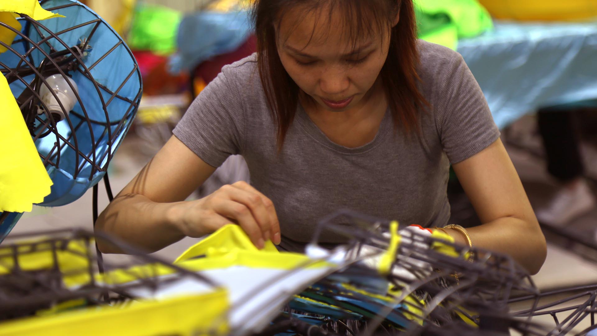 Chinese lantern manufacturer artisan hand wrapping silk fabric on steel frame in Zigong workshop