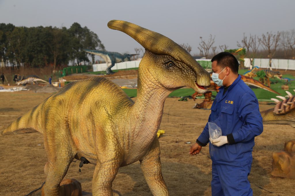 Technician performing routine maintenance on animatronic dinosaur exhibit