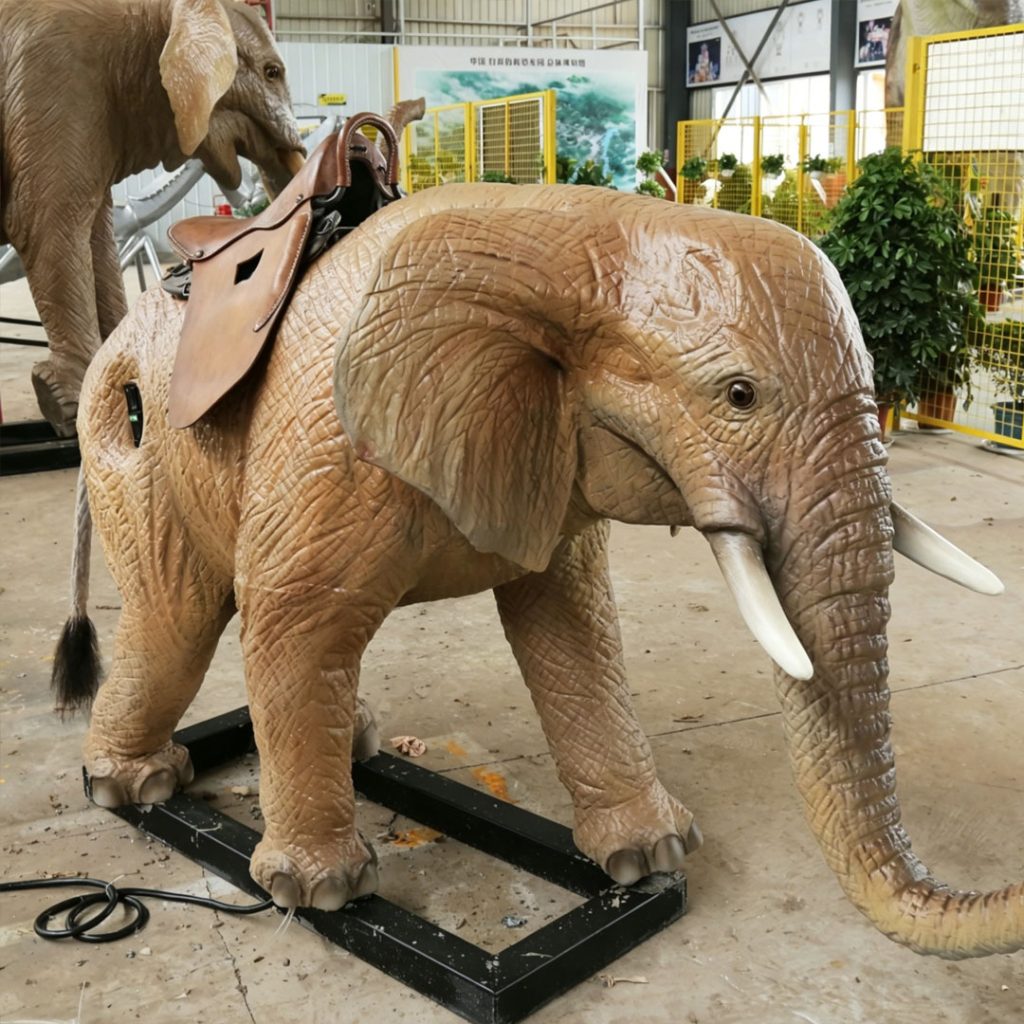 Ride-on animatronic baby elephant with leather saddle and safety handles designed for children's interactive rides in indoor entertainment setting