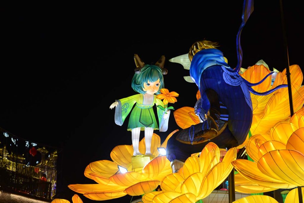 Illuminated flower fairy lantern with butterfly details glowing in a botanical garden night display