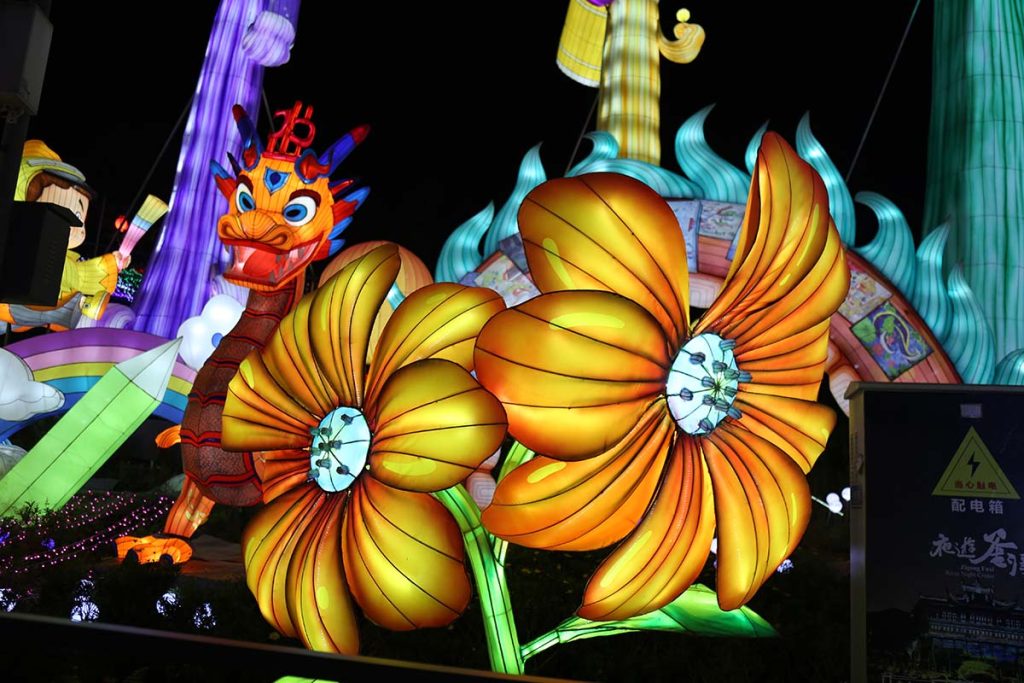 Giant illuminated sunflower lantern glowing with golden petals in a botanical garden night display