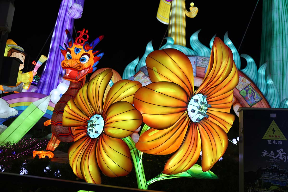 Sunflower lantern — giant illuminated sunflower with golden petals glowing in a botanical garden display at night