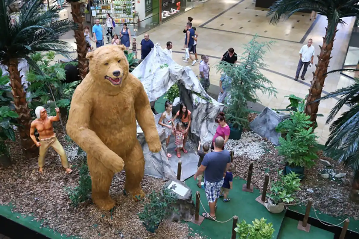 Animatronic cave bear model displayed in shopping mall with visitors and prehistoric scene props