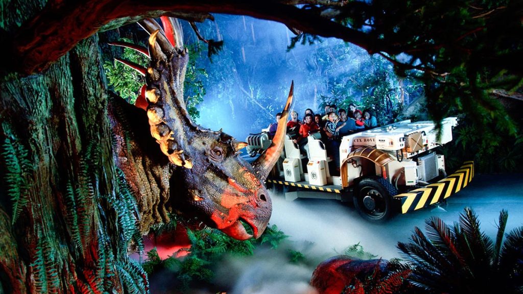 Visitors riding a guided animatronic dinosaur tour through a themed park attraction trail
