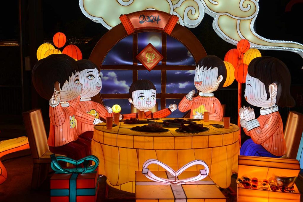 Illuminated family reunion dinner lantern sculpture showing four family members at a round table with the 福 (fortune) character, a hallmark Chinese New Year family reunion scene