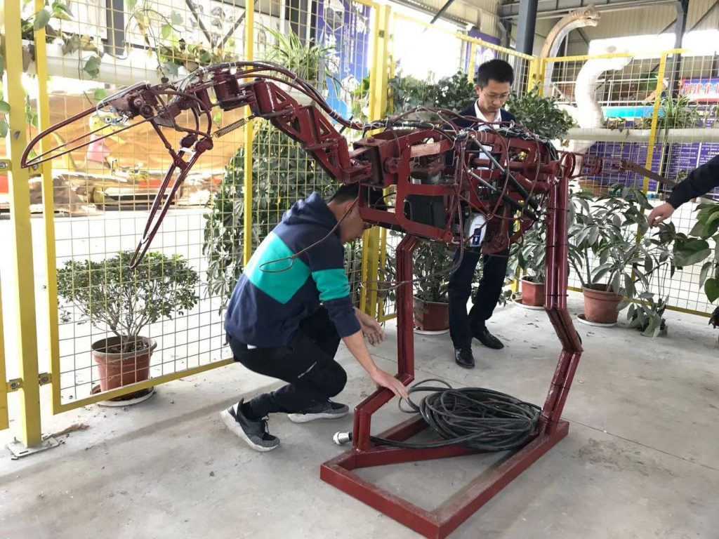 Behind-the-scenes view of animatronic dinosaur internal steel frame with body-mounted sensors cables and electronic control system
