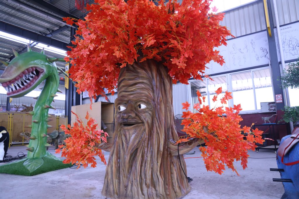Interactive storytelling simulated tree character with friendly face and orange maple leaves used as theme park or family attraction storytelling prop