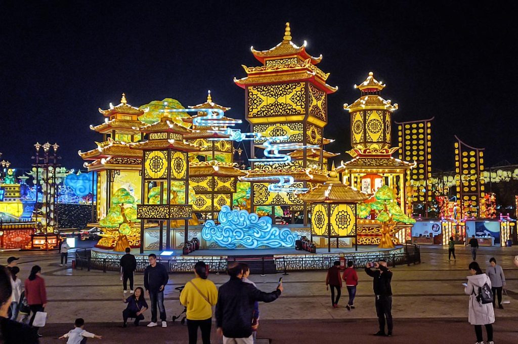 Visitors walking through illuminated moon palace tower display at mid-autumn lantern festival