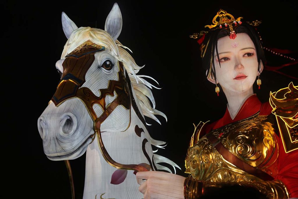 Close-up of a giant lantern horse's head and a female figure in traditional armor, showing long continuous (parallel-following wires) defining the horse's mane, facial muscles, and the woman's flowing hair and shoulder