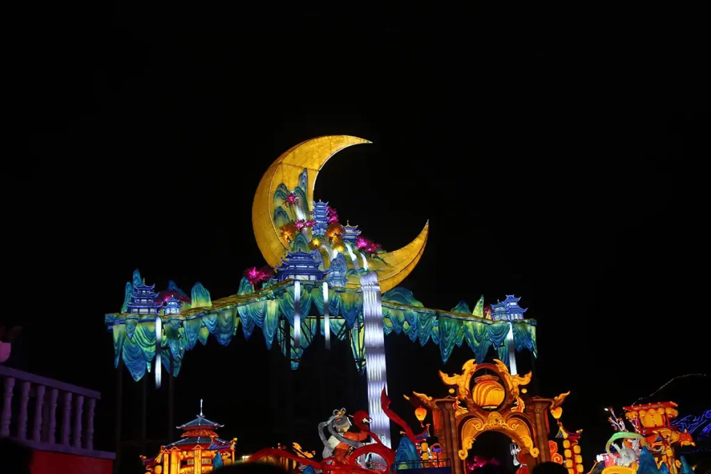 Giant illuminated crescent moon hovering above a classical Chinese palace facade with cascading waterfalls, misty mountains, and traditional figures at night during Mid-Autumn Festival
