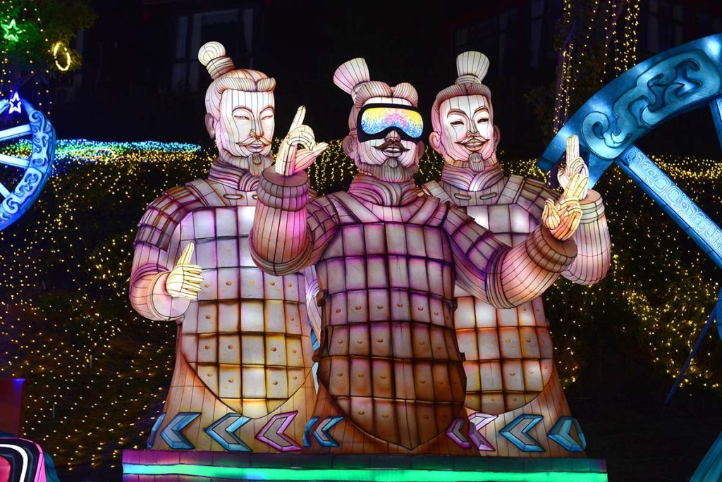 Three terracotta warrior style programmable RGB LED lanterns with detailed character features and pink-to-warm color gradient at night festival