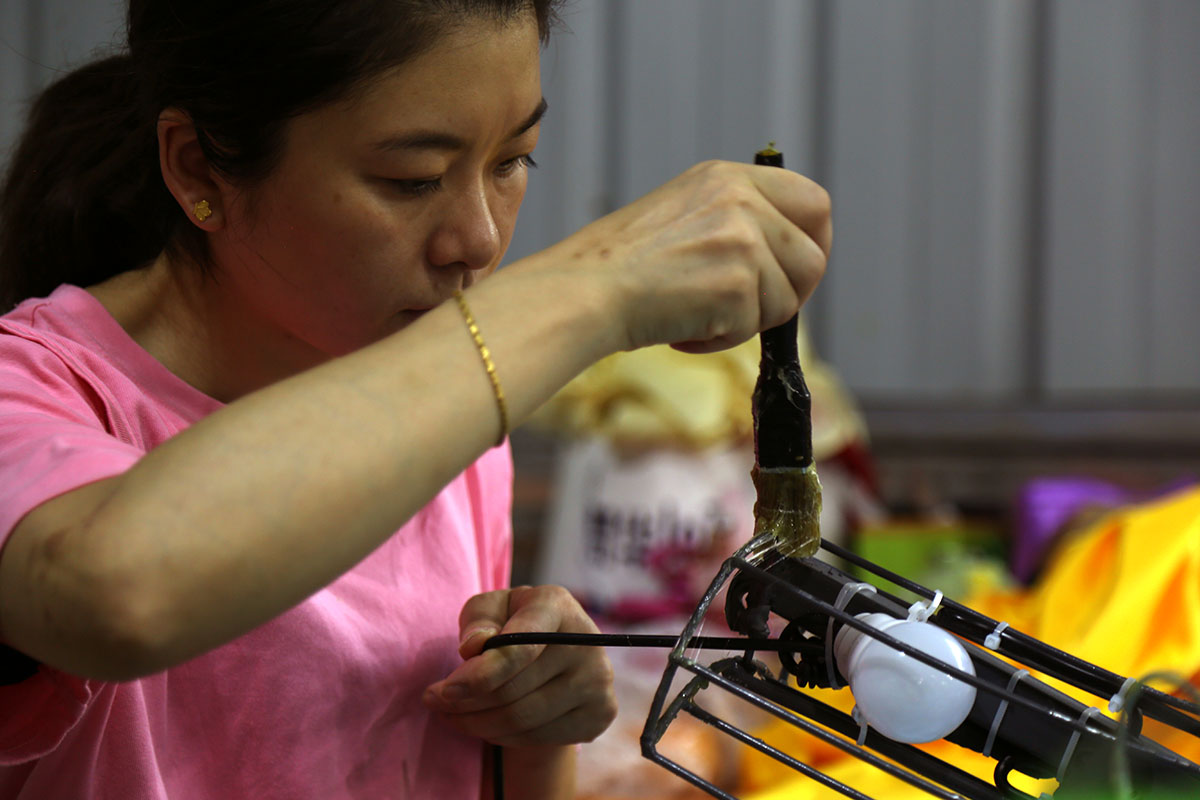 Craftsman applying glue on lantern frame before pasting satin fabric
