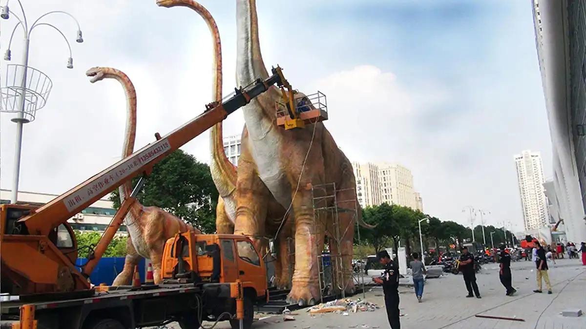 Crane lifting a 20-meter animatronic brachiosaurus during outdoor shopping mall installation in Nanjing