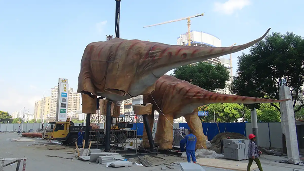 Two adult animatronic brachiosaurus being connected on a mall plaza during the outdoor installation