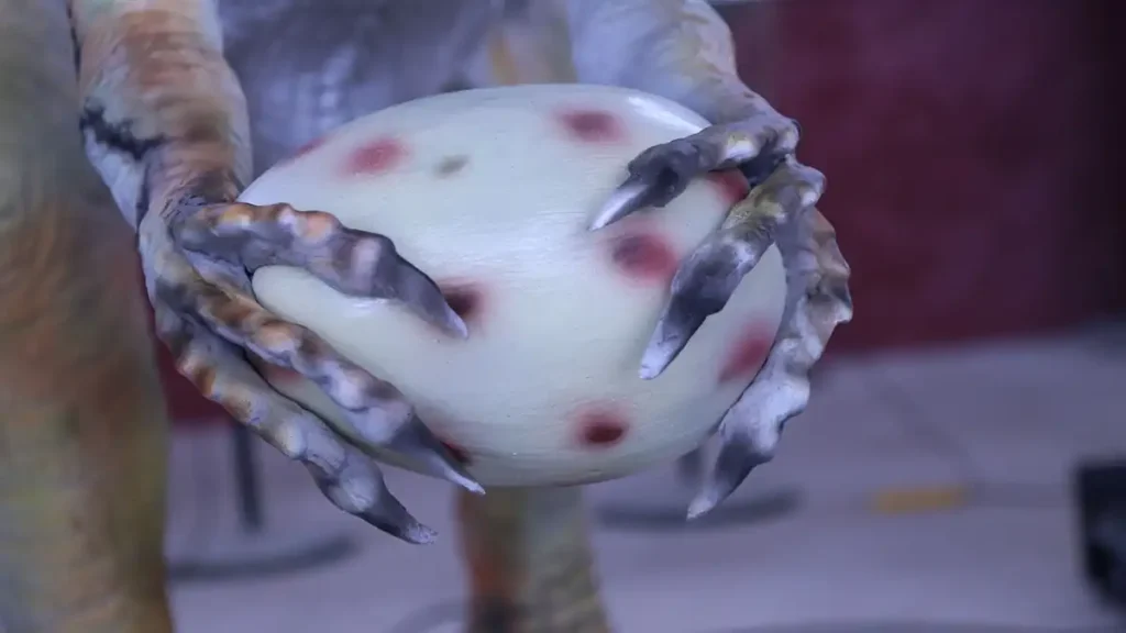 animatronic oviraptor claws holding spotted egg