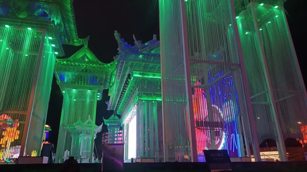 Architectural light sculpture illuminating a building facade with layered LED colors at night