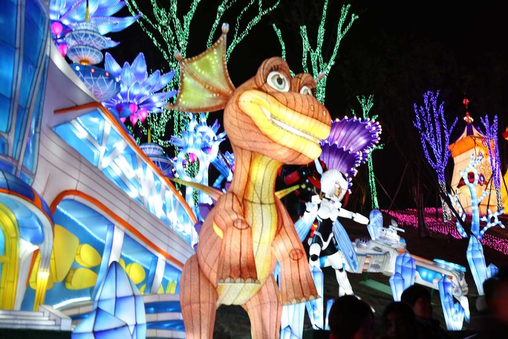 Cartoon dinosaur lantern display in a fantasy space-themed light festival scene