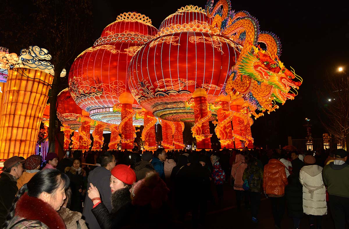Giant red lantern cluster with dragon decoration and crowds at a night festival