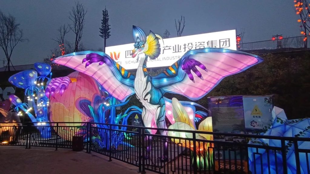 Dinosaur lantern display with illuminated dinosaur sculptures glowing along a theme park night trail