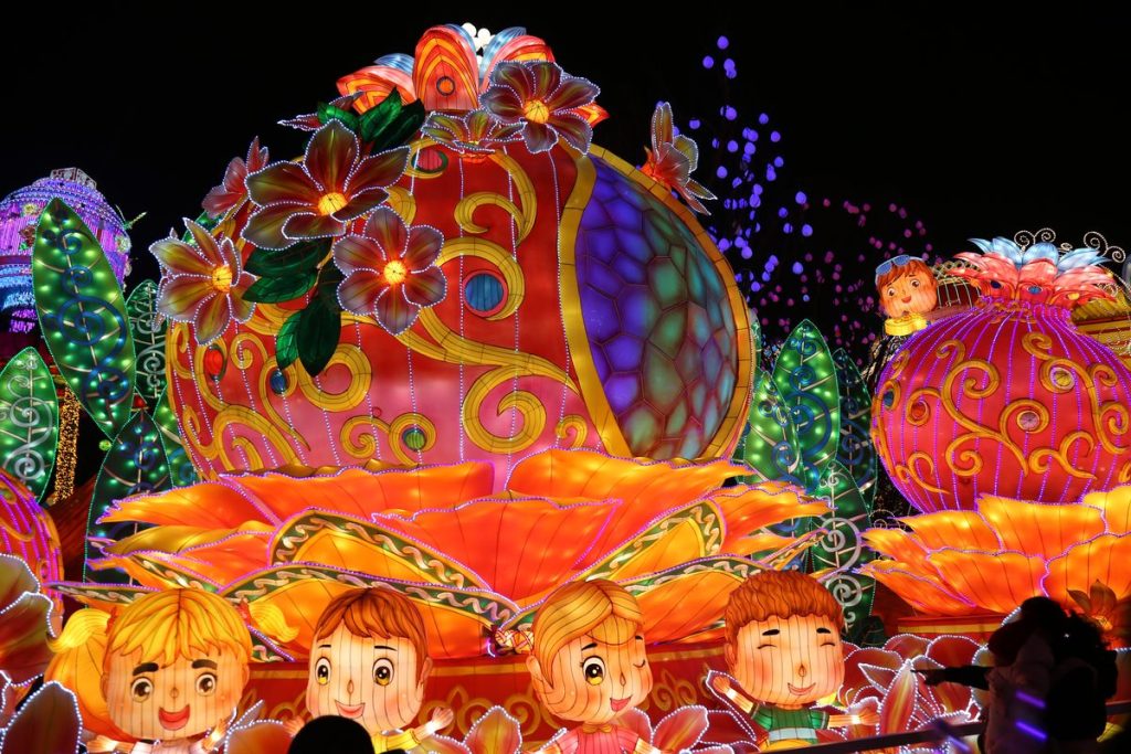 Giant Chinese fortune bag lantern decorated with flowers and surrounded by child figures at a lantern festival