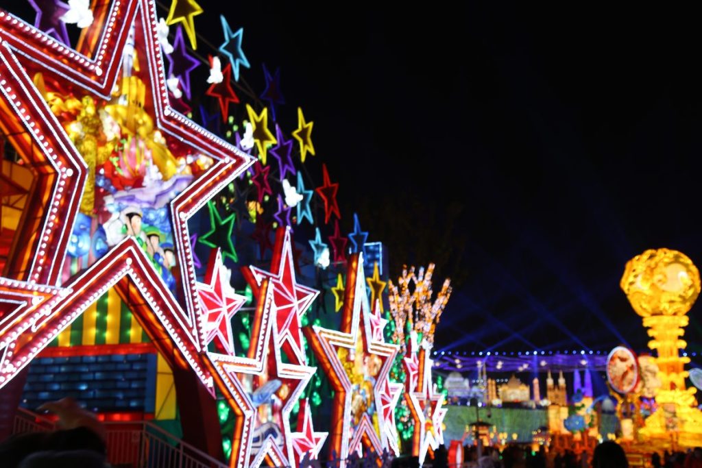 Colorful star lantern arch forming a walk-through light tunnel at a holiday festival at night