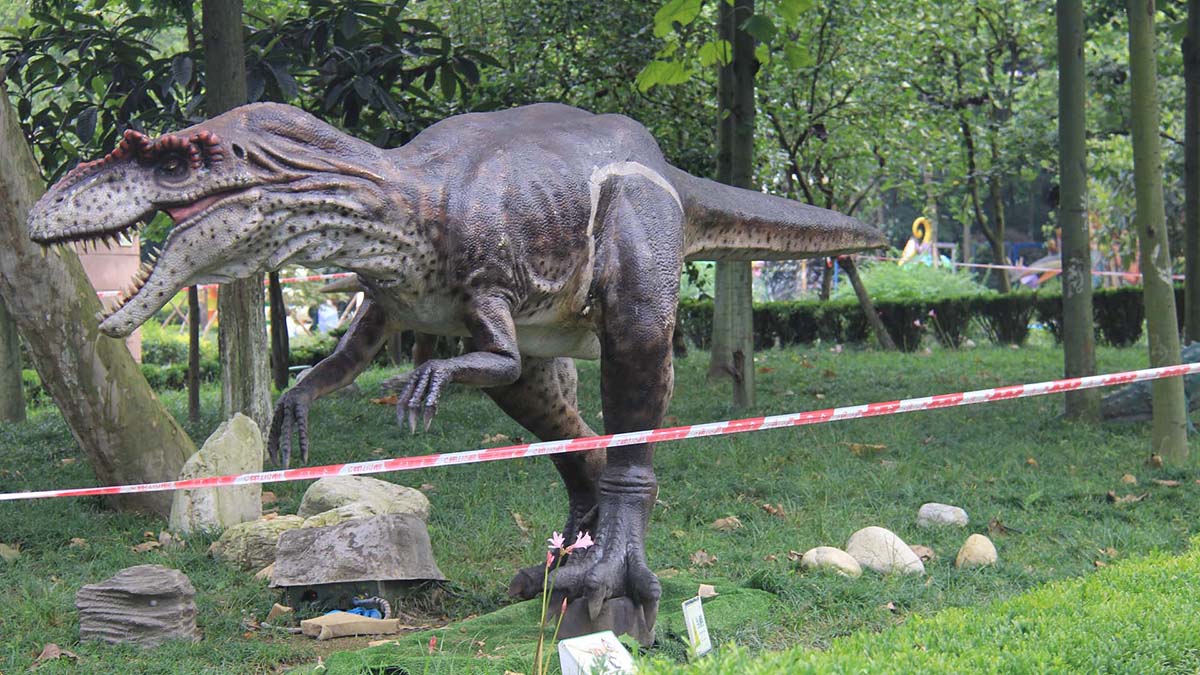 FestiveLanterns interactive animatronic dinosaur mid-run pose in a forest-themed outdoor park, with open jaw and motion blur