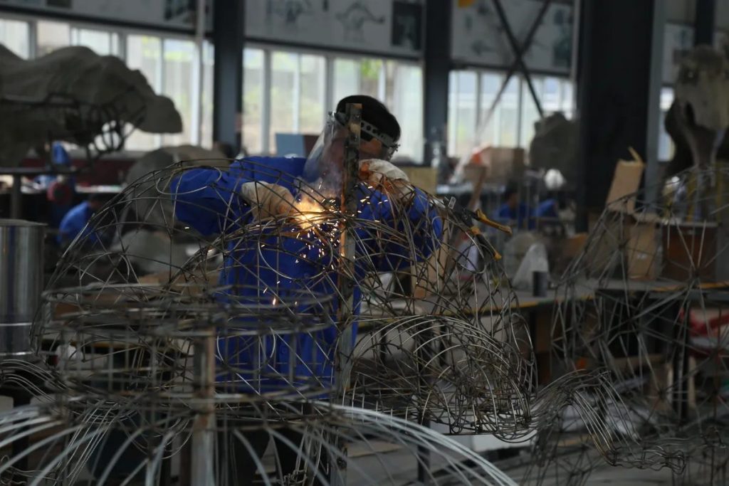 Workers assembling a steel-frame lantern structure in a fabrication workshop