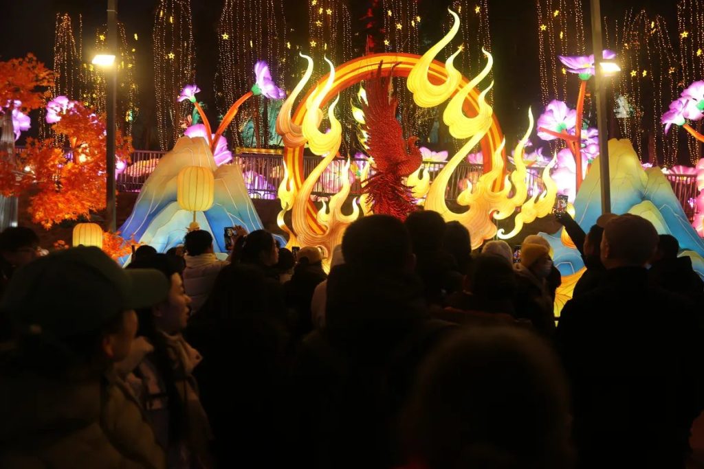 Families walking past glowing lantern arches at a busy winter festival
