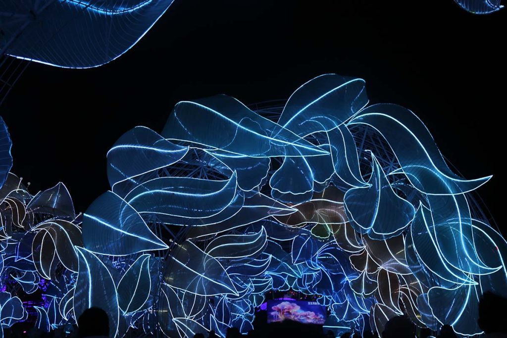 Festival visitors watch glowing LED-line animal sculptures in blue and violet at a FestiveLanterns lantern festival tunnel display
