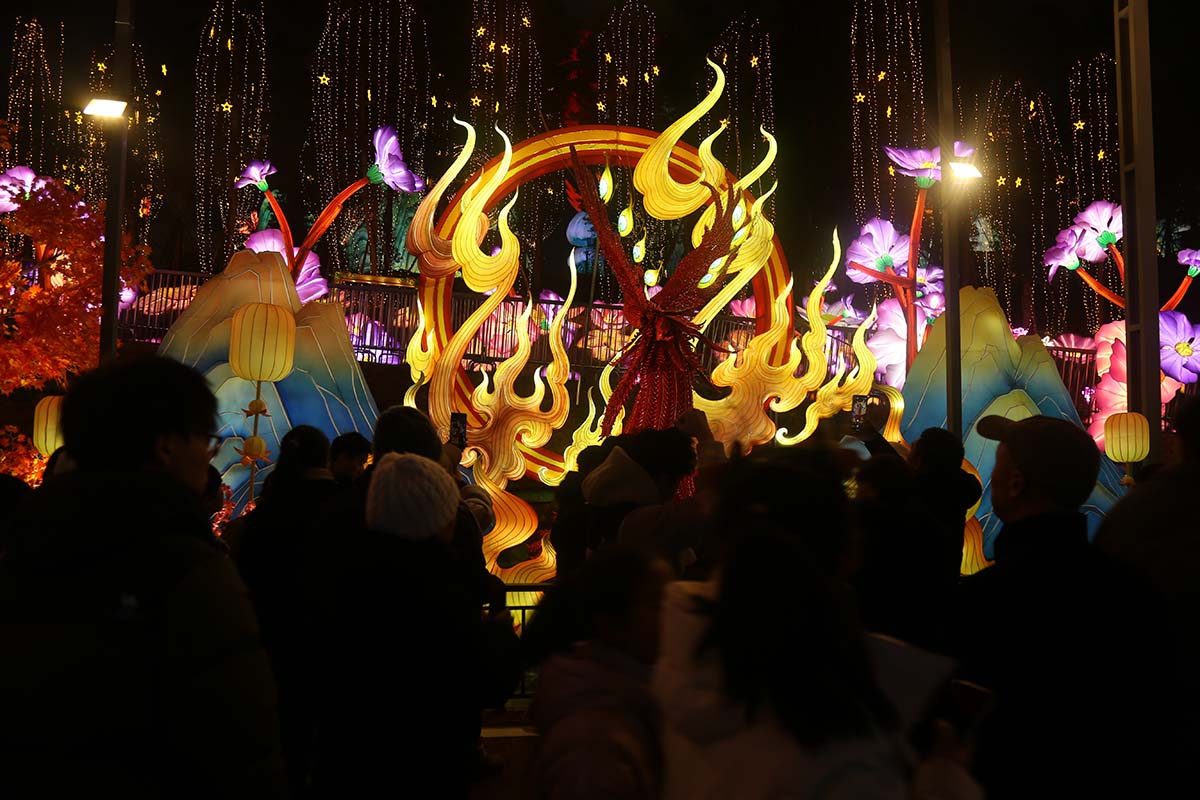 A crowd of festival visitors gathering around a glowing red-and-gold traditional Chinese lantern centerpiece at a FestiveLanterns lantern festival