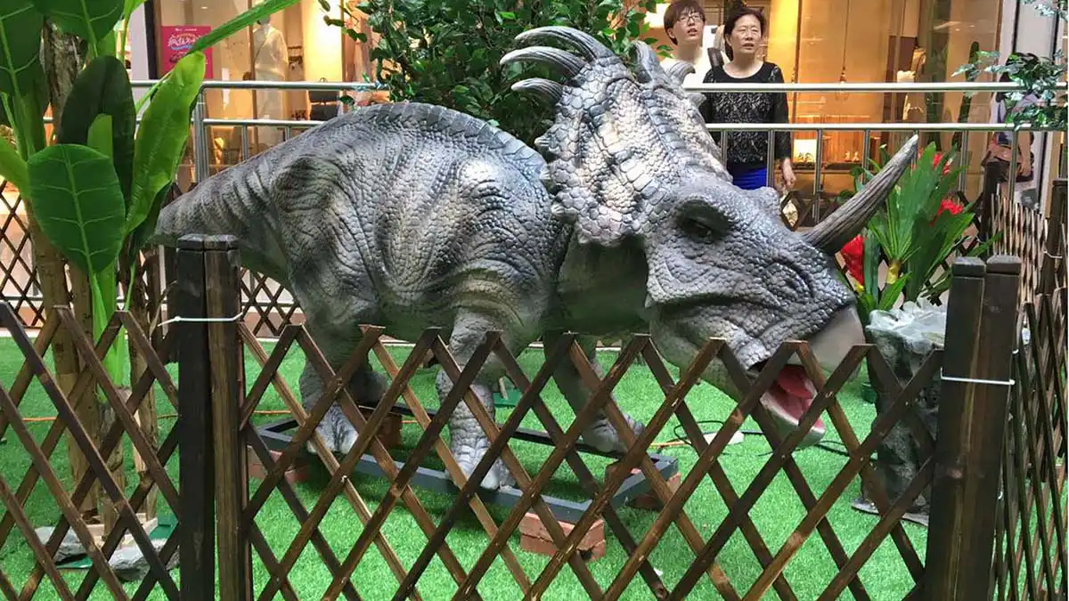 FestiveLanterns Triceratops animatronic in a shopping mall display with decorative plants and a bamboo fence — plug-and-play setup