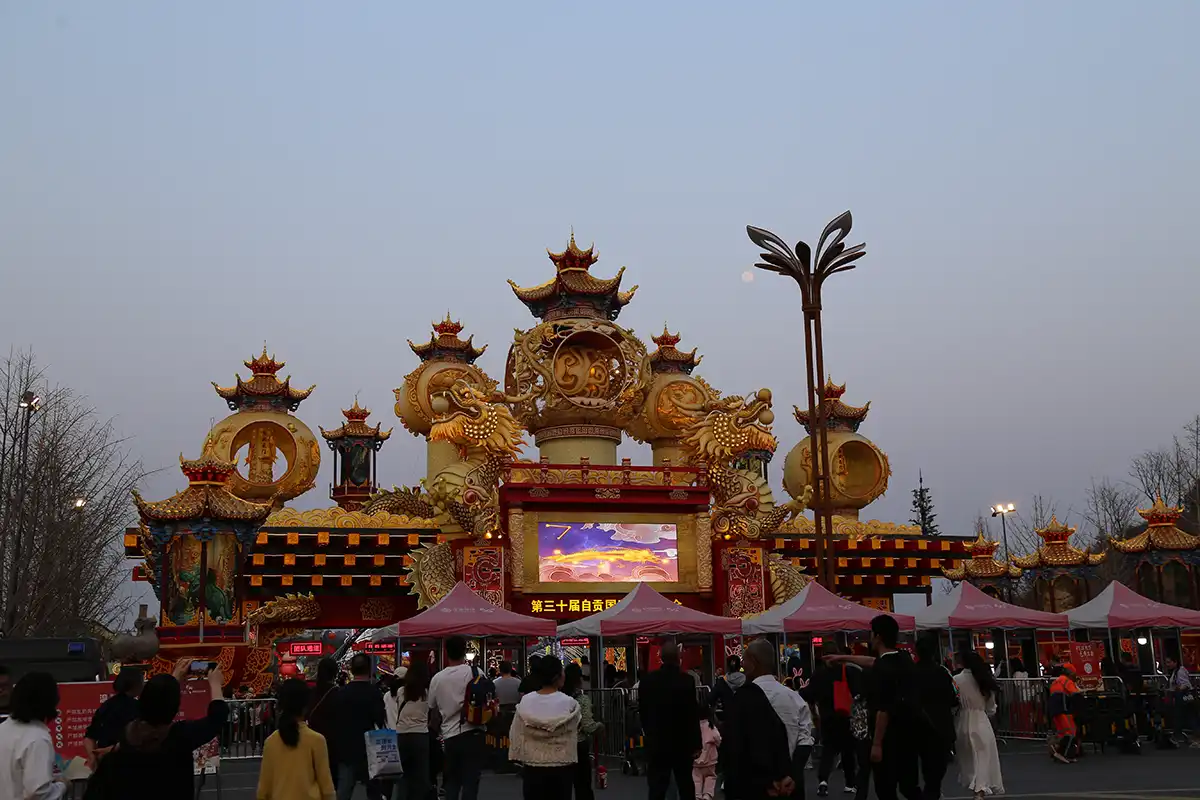 Custom lantern design process — illuminated palace arch entrance gate with dragons and pagoda roofs at a city lantern event