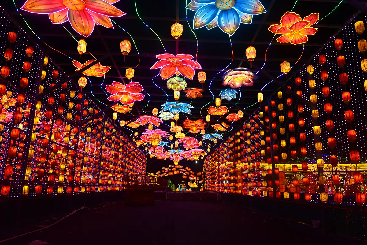 FestiveLanterns themed lantern walkway tunnel — silk flowers, vine lights and hanging lanterns creating a walkable light corridor for a botanical garden night event