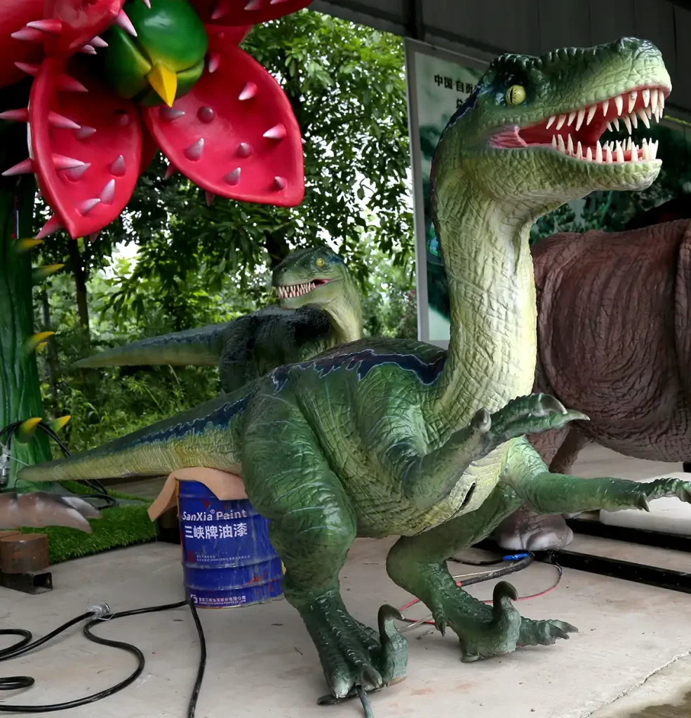 Front view of outdoor Velociraptor display statue with jaws open showing hand-painted teeth