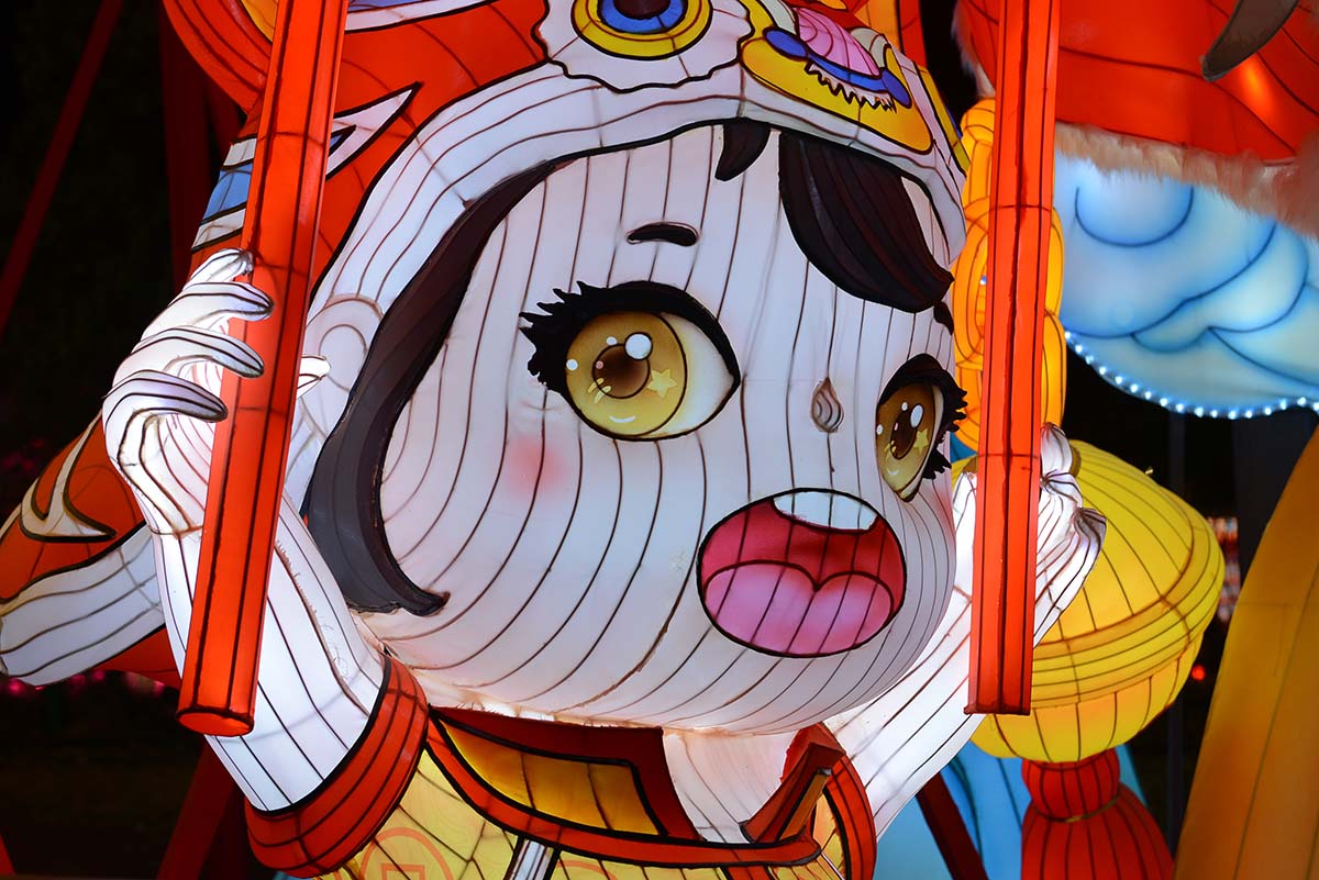 Close-up of a giant traditional Chinese lantern doll head with Peking opera headdress and oversized eyes, a signature centerpiece for Lunar New Year lantern festivals