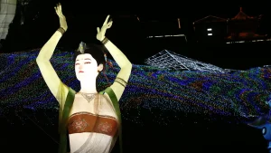 Flying fairy lantern festival with a celestial dancer silhouette in flowing robes suspended above a glowing Chinese lantern festival night scene