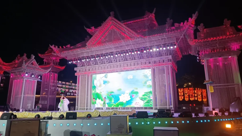 Lantern festival stage with an illuminated palace facade, tiered pink roofs and a central LED screen
