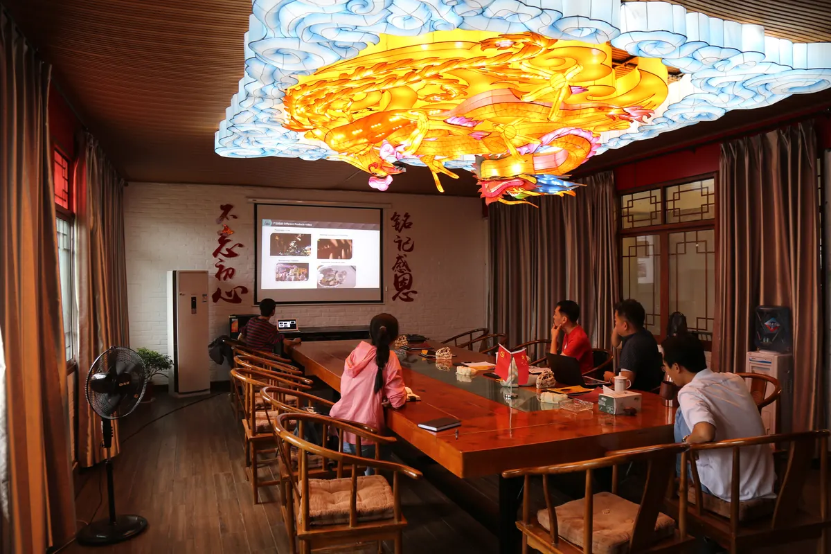 Design review meeting under a giant dragon lantern ceiling at the FestiveLanterns office in Zigong