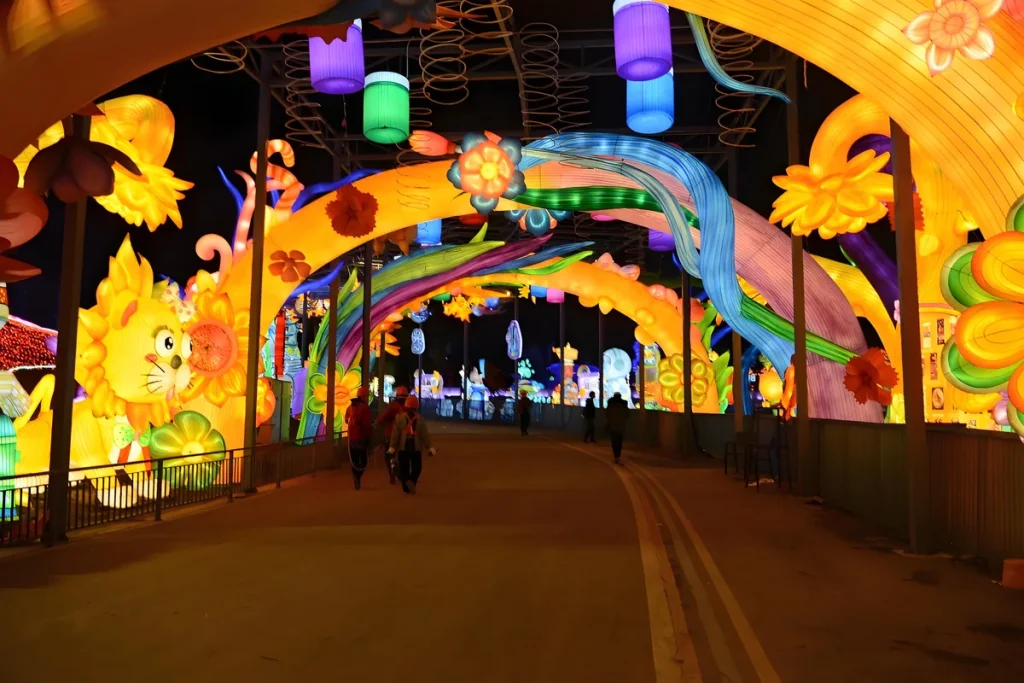 Flower lantern tunnel corridor with silk peony, lotus and chrysanthemum blooms over visitors walking through