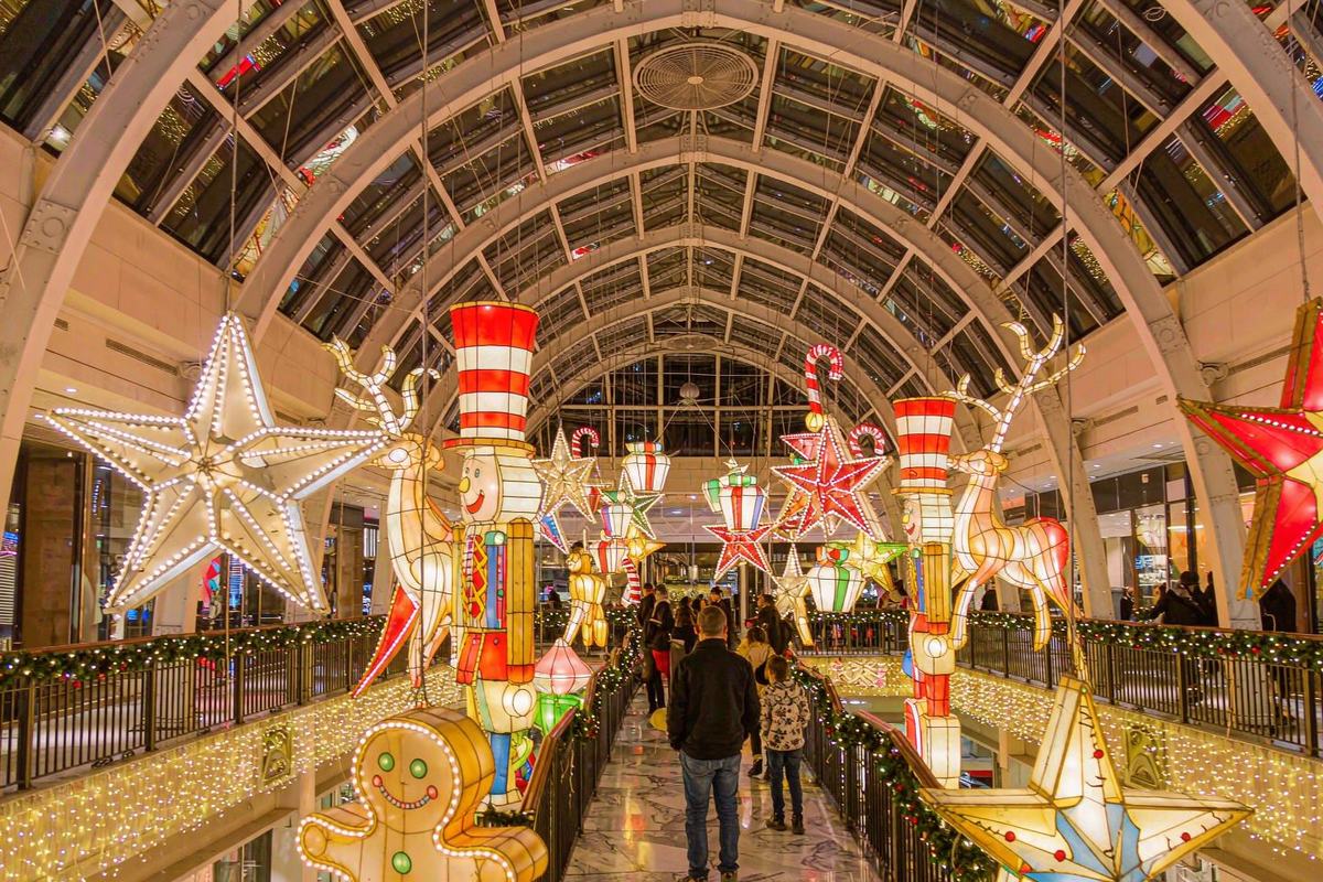 Suspended festive lanterns including soldiers, reindeer and ornament motifs in a covered atrium